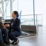 Power wheelchair user discussing safe assistance and mobility-aid handling with airport staff